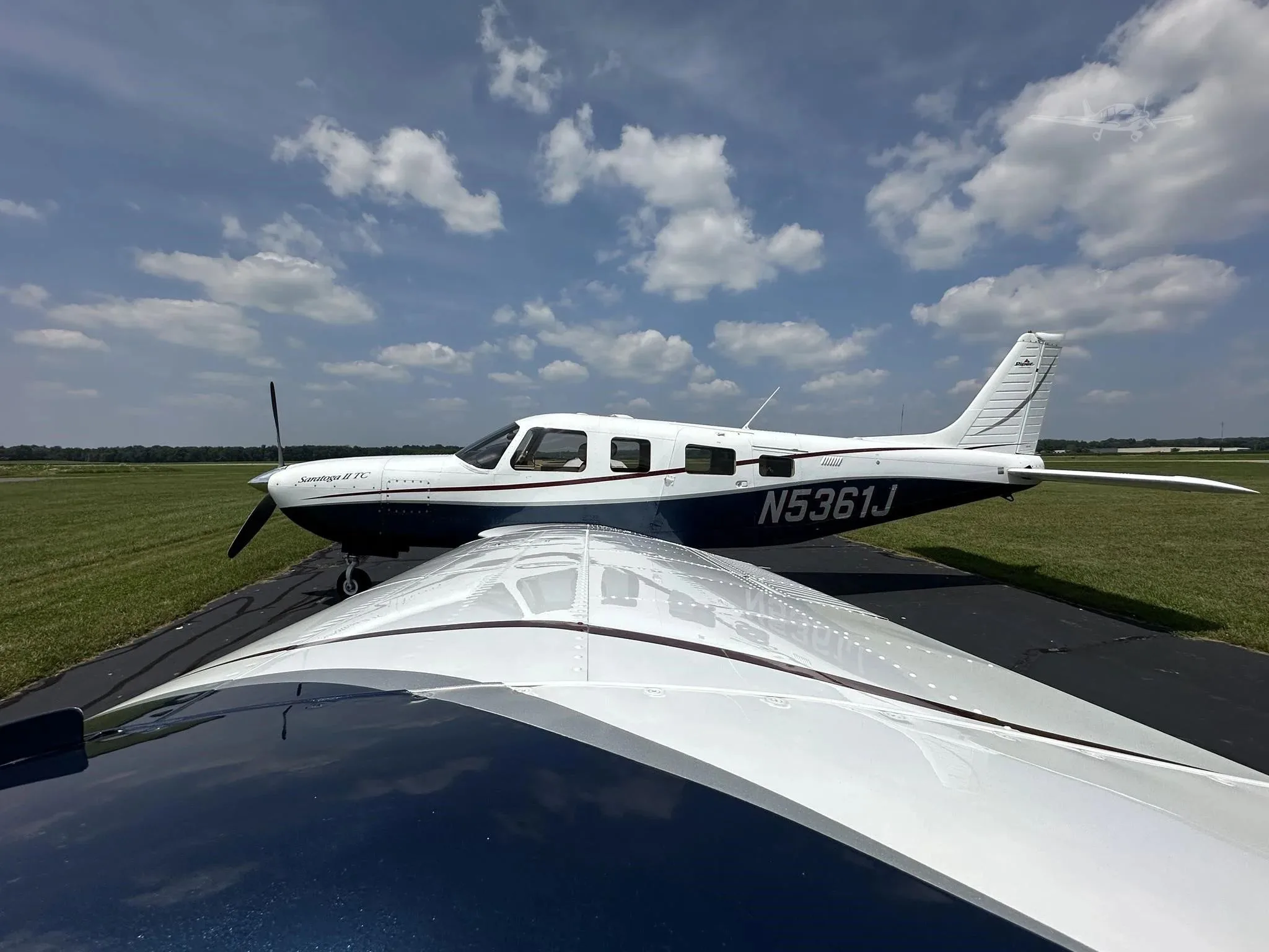 A unique perspective from the wing of the white and blue Piper Saratoga II TC (N5361J) on an airfield.