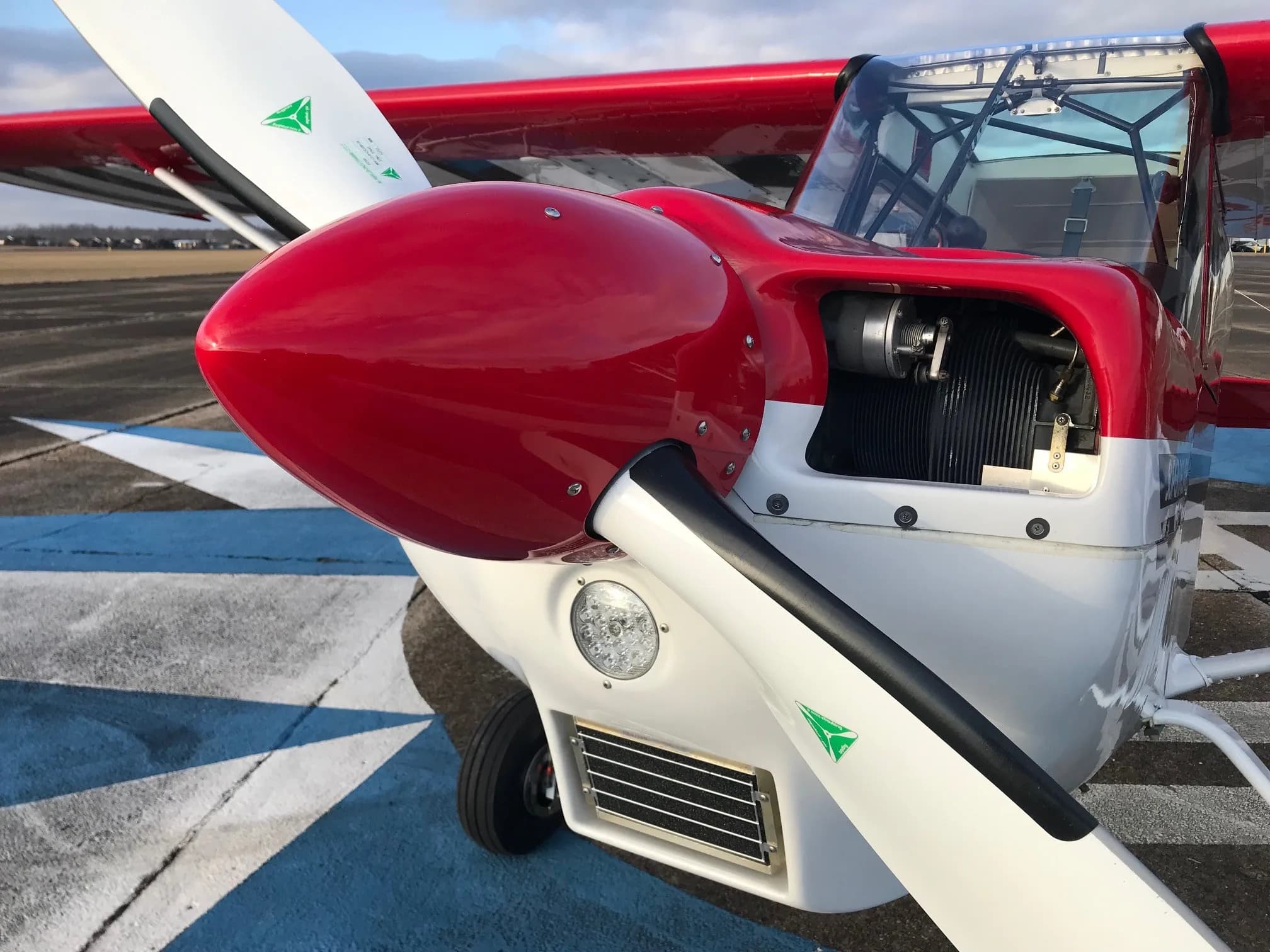 A close-up view of the red propeller spinner and white engine cowling of the Super Decathlon aircraft.