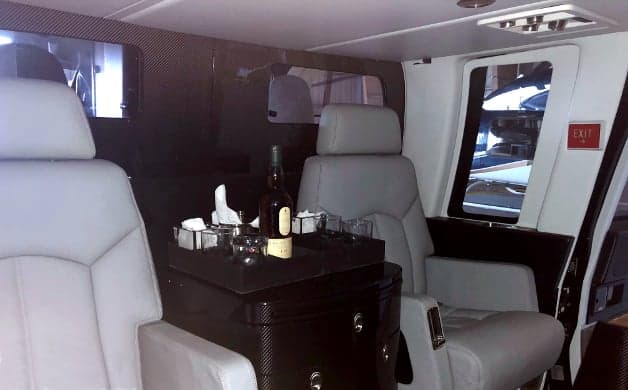 Interior view of the helicopter with leather seats and a table with drinks.