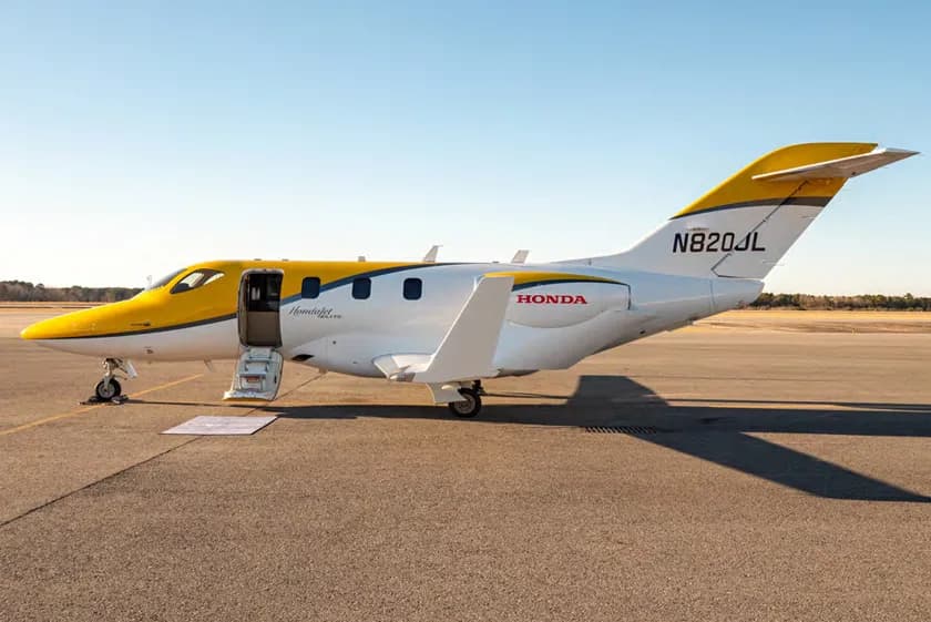 HondaJet Elite S with a yellow and white paint scheme parked on the tarmac with the door open.