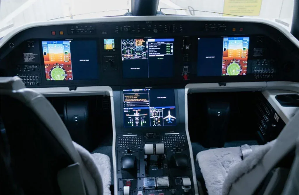 The modern glass cockpit of an Embraer Praetor 600, displaying multiple digital screens with flight information.