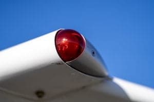 Close-up of the red navigation light on the wingtip of a Piper Super Cub aircraft.