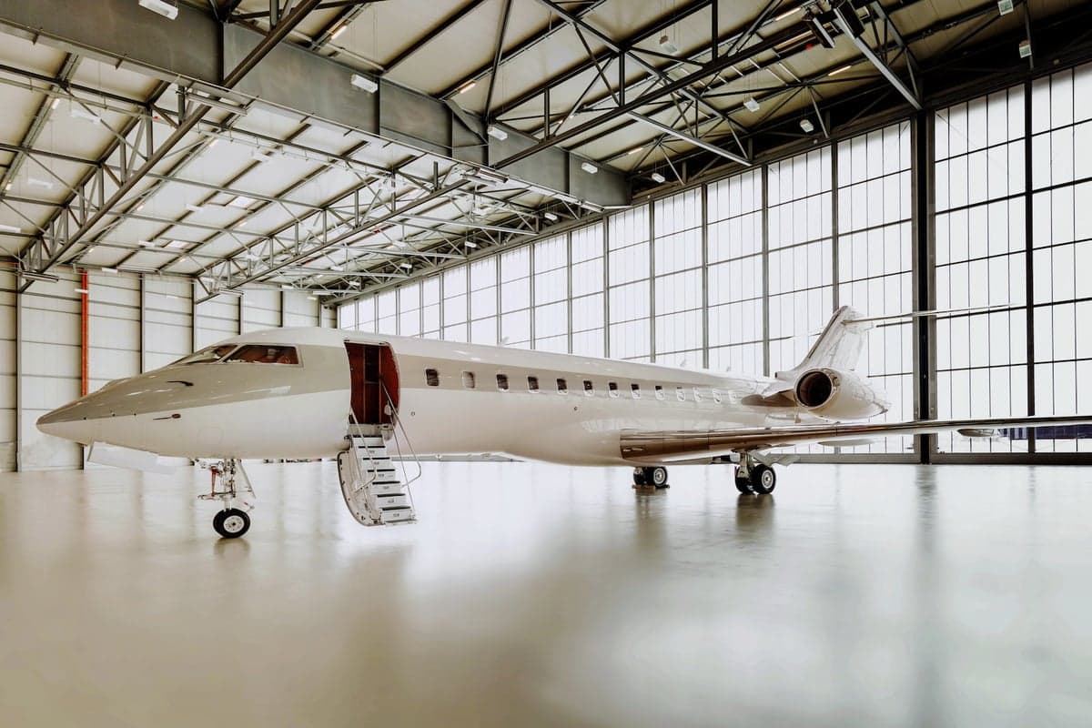 A Global Express aircraft is parked inside a hangar with the boarding stairs down.