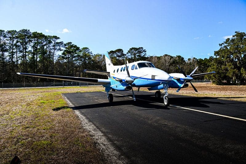 A Beechcraft King Air sits on the tarmac in the sunshine.