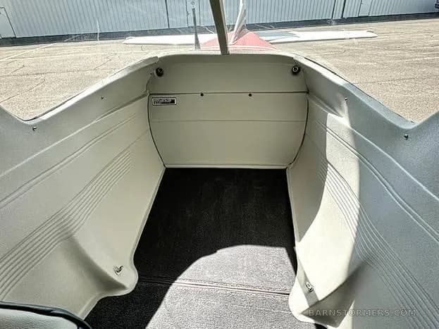 The empty baggage compartment of a small aircraft with light gray walls and dark gray carpet.