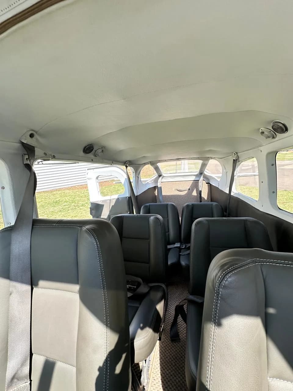 The aircraft interior cabin with multiple rows of dark grey leather passenger seats.