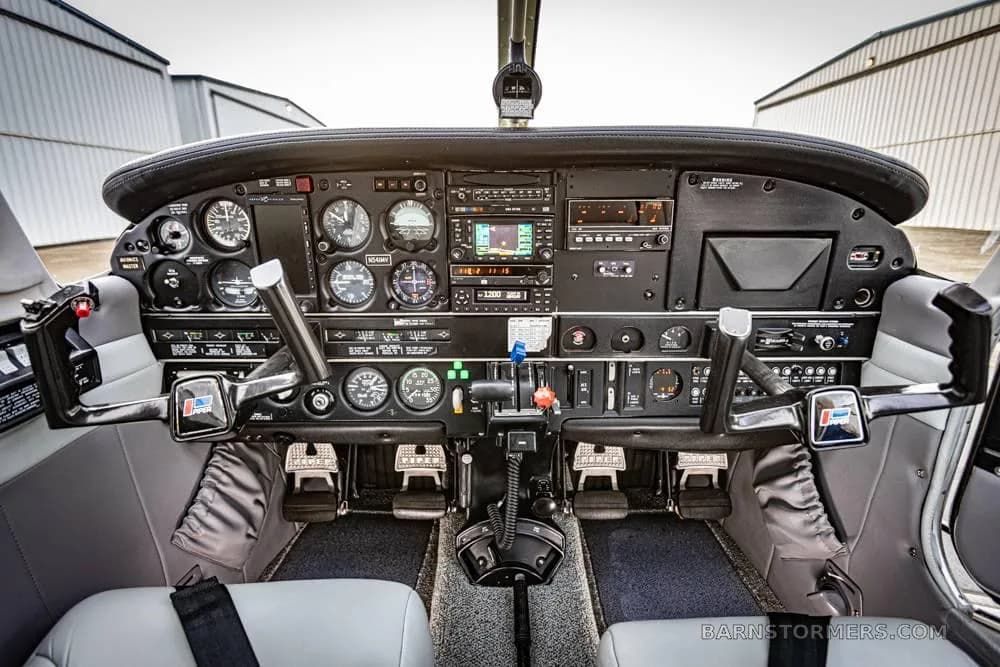 The cockpit of a small aircraft, showing the instrument panel, dual yokes, and center console.