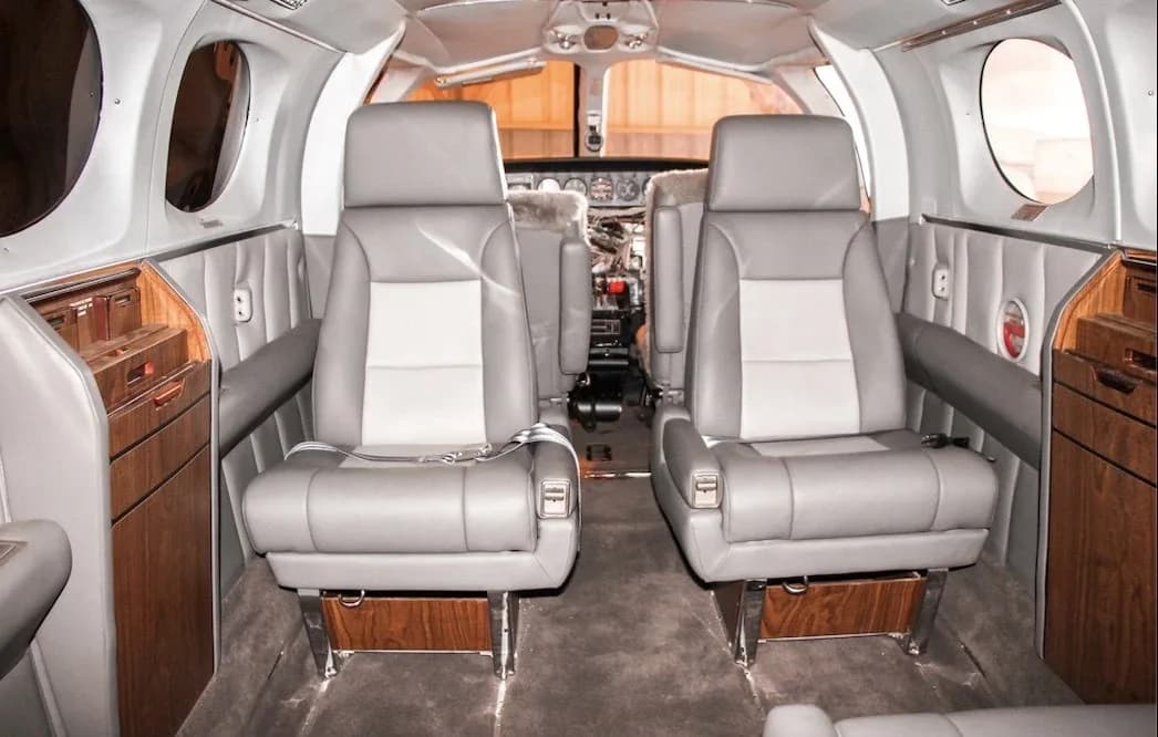 The aircraft's cabin interior with gray and white leather seats and wood paneling.