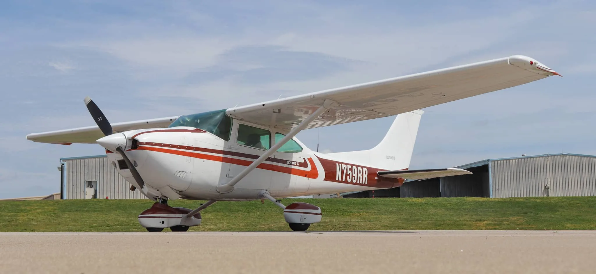 A side view of the Cessna Skylane S (N759RR) with its white and brown paint scheme on an airfield.