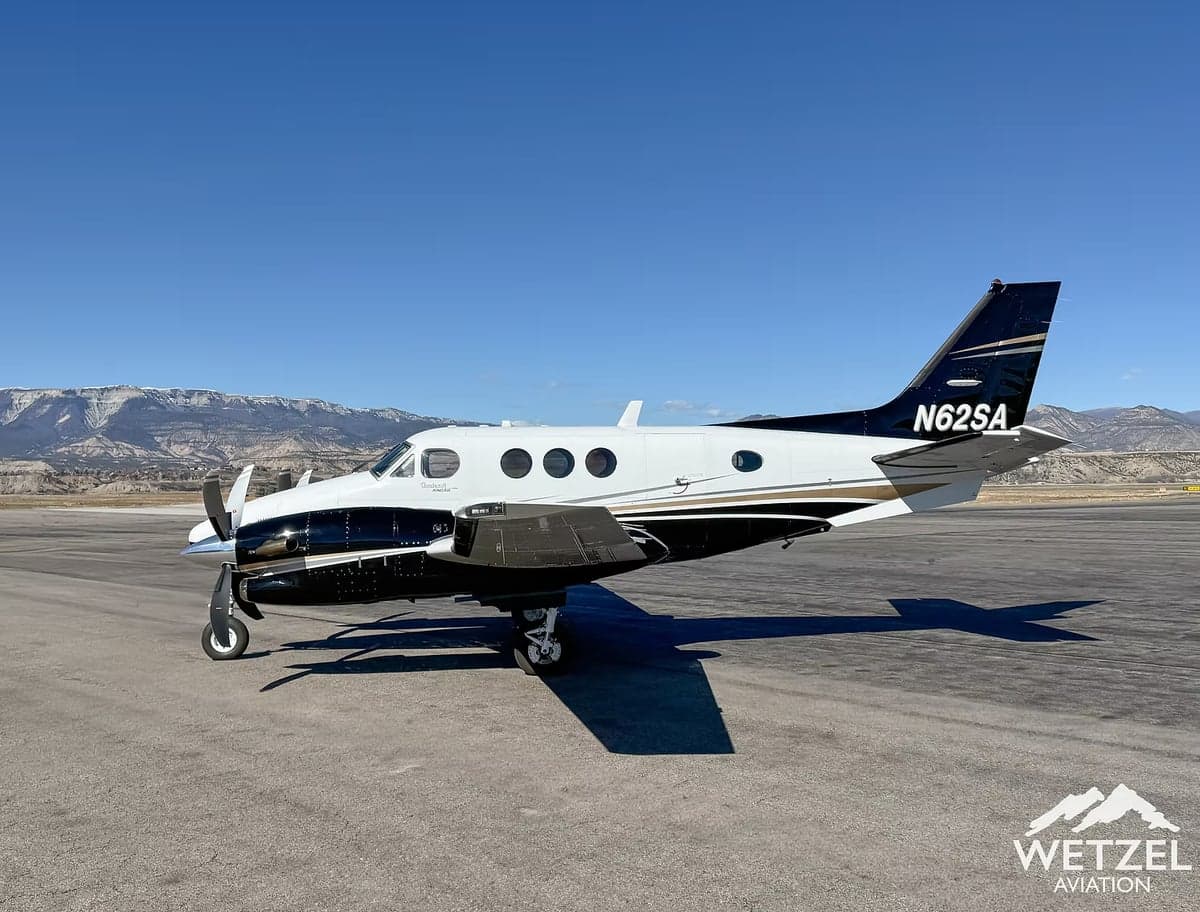 A side view of a black and white twin-engine turboprop aircraft, N62SA, parked on an airfield.