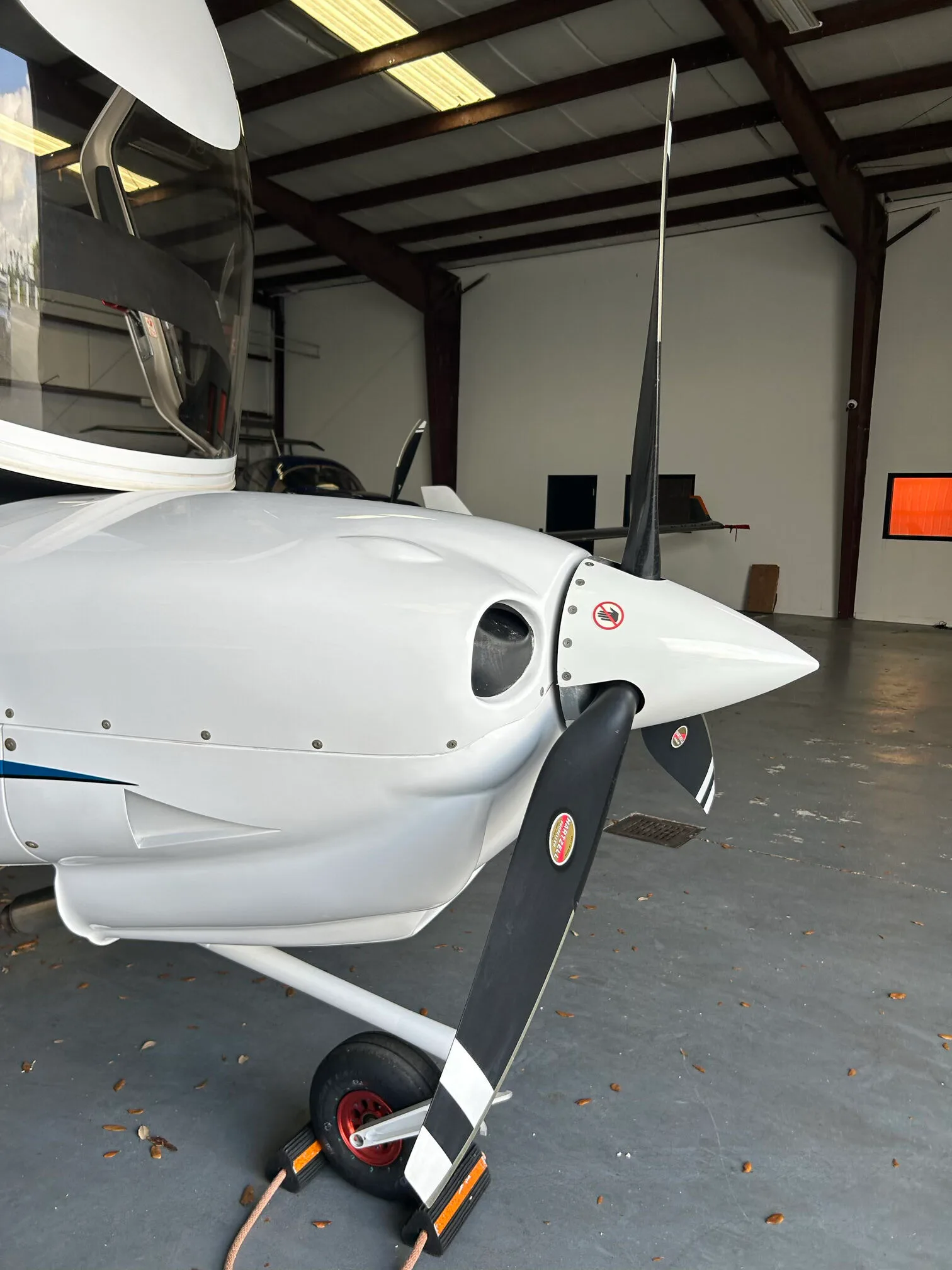 Close-up view of the nose and propeller of a white Diamond DA40 aircraft in a hangar.