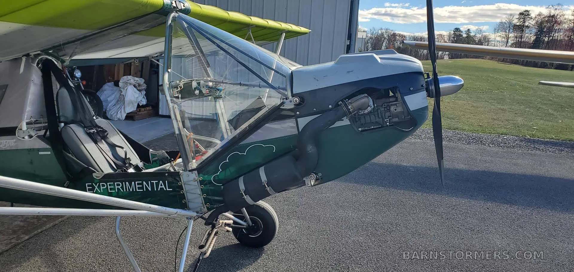 A close-up view of the front-right side of a green and white experimental aircraft, showing the engine cowling and open cockpit.