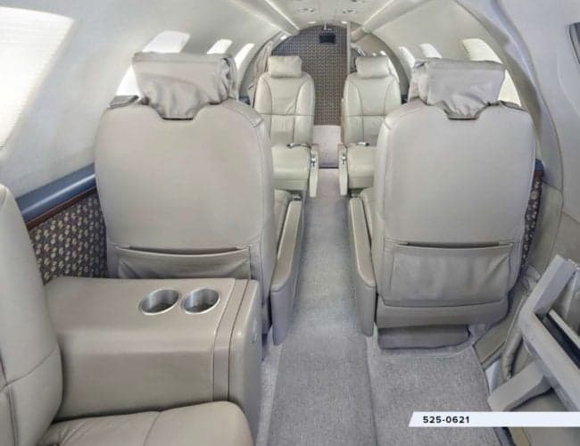 The interior of the aircraft features leather seats and a side table with cupholders.