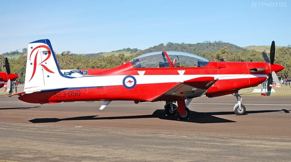 A23-050 aircraft in flight with red and white paint scheme.