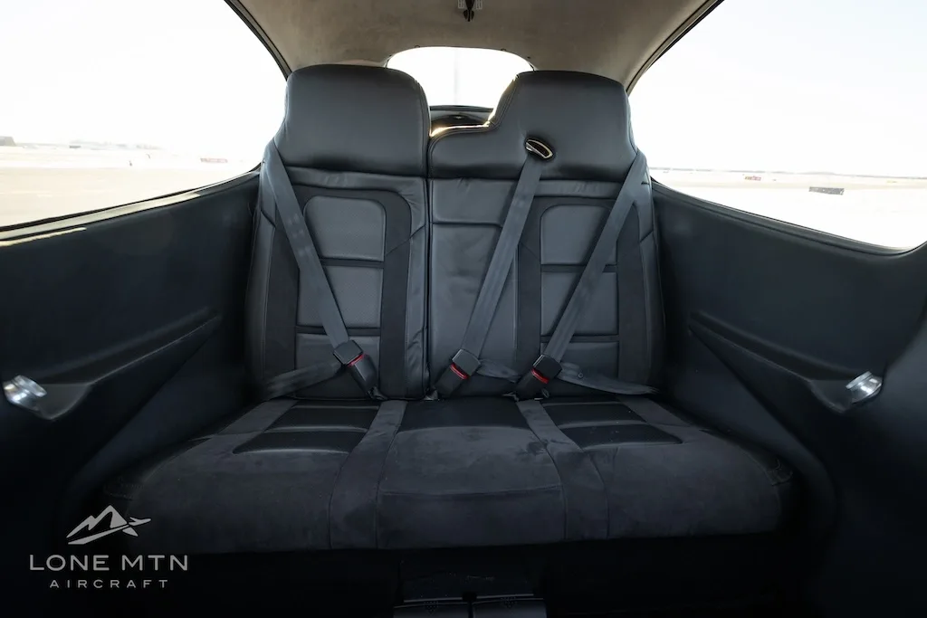 The black leather rear seats of the aircraft cabin with seatbelts.