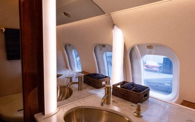 Aircraft cabin interior with wood trim and cream-colored seats.
