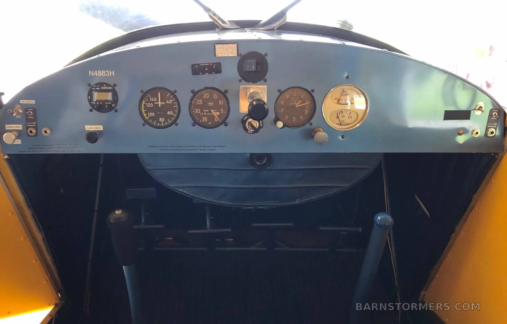 The blue instrument panel of a yellow aircraft, showing various gauges and controls.