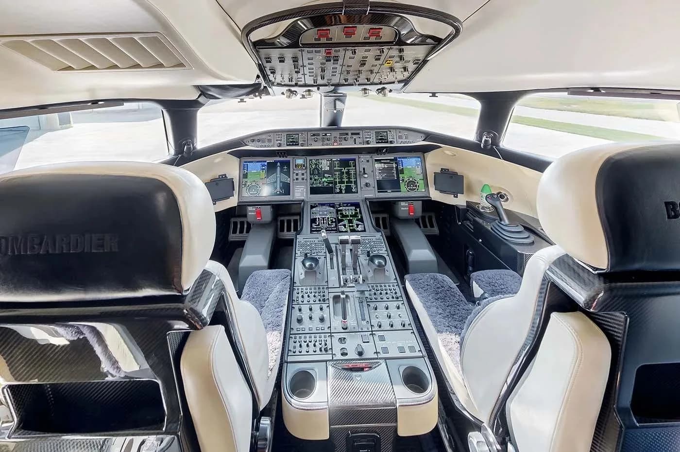 The modern cockpit of a Bombardier Global business jet with multiple display screens and a central control panel.
