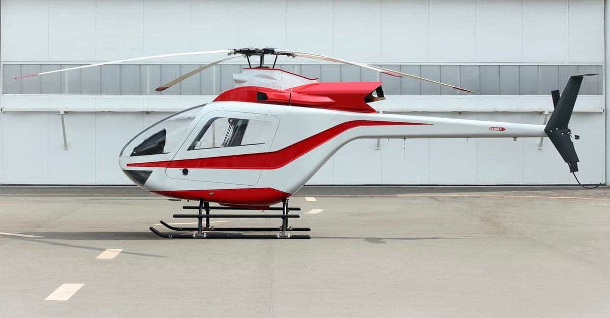 A side view of the white and red helicopter on the tarmac.