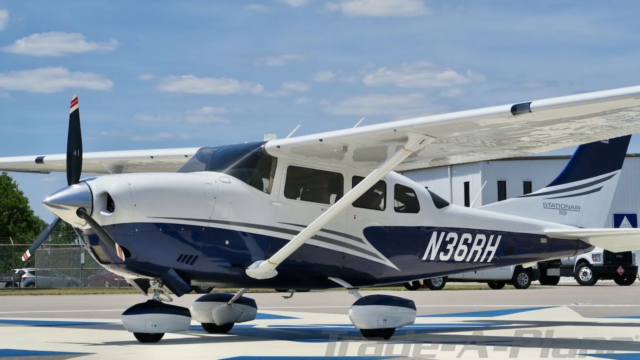 Front-left view of a white and blue Cessna Stationair HD (N36RH) on an airfield.