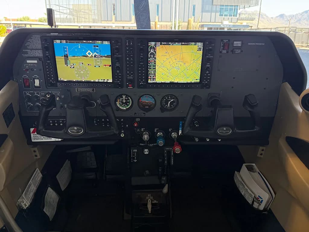 The modern glass cockpit of the aircraft, featuring dual large display screens and control yokes.