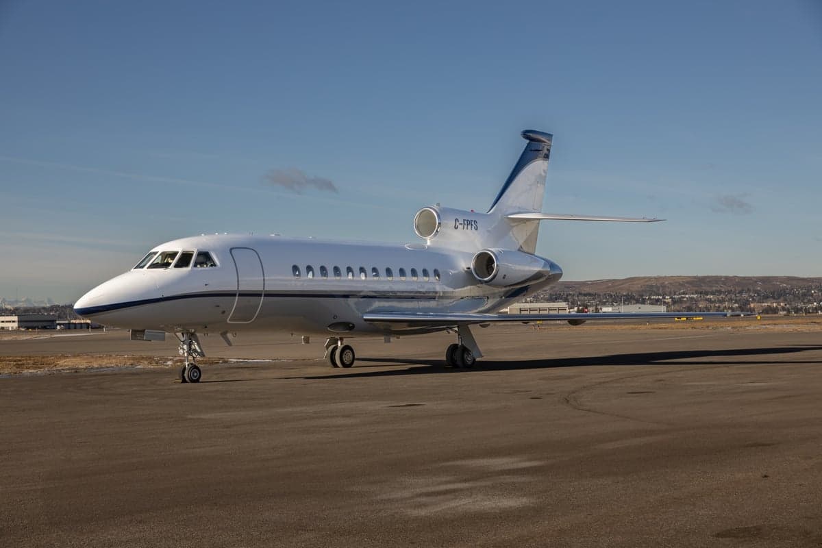 A Dassault Falcon aircraft with registration C-FPFS is parked on the tarmac.