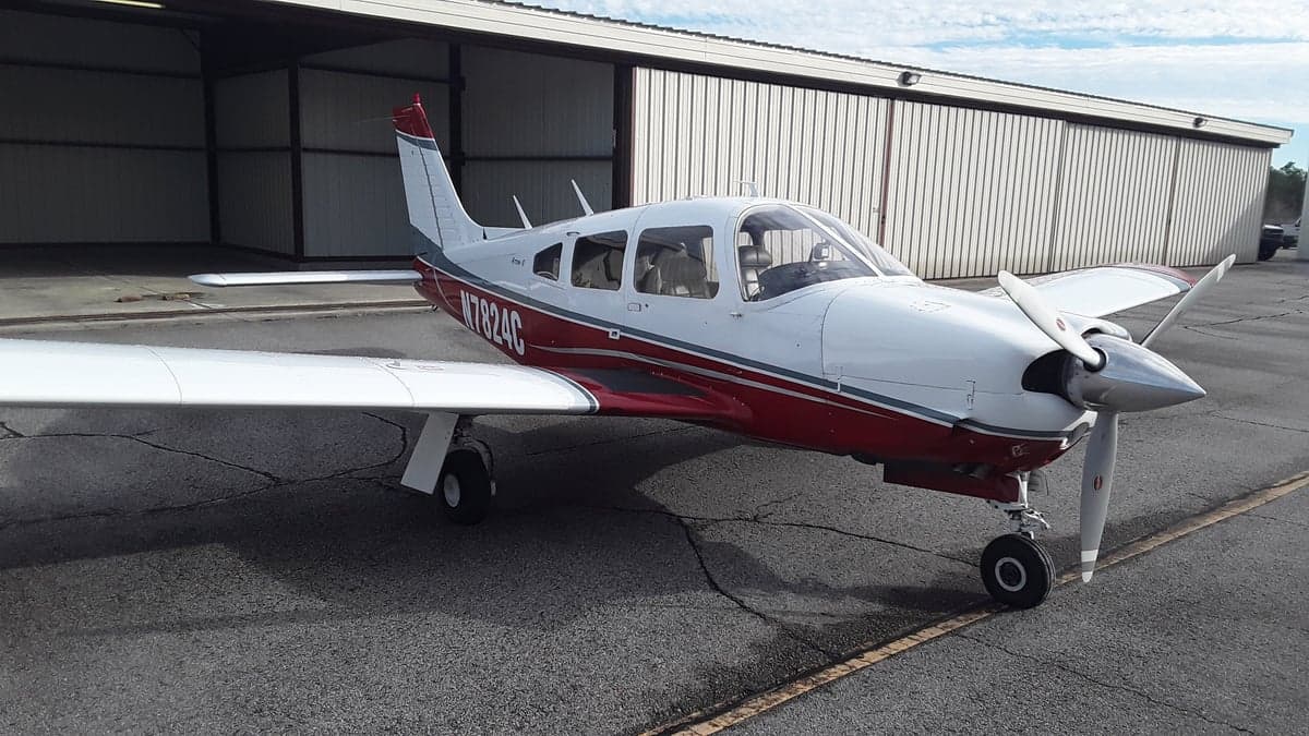 Front view of a white and red Piper PA-28 with registration N7824C parked on the tarmac.