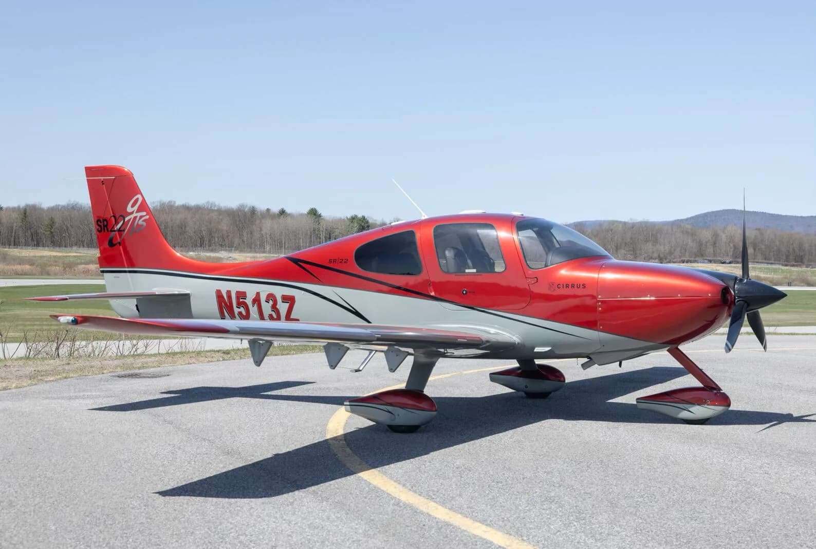 A red and grey Cirrus SR22T aircraft (N513Z) parked on an asphalt runway.