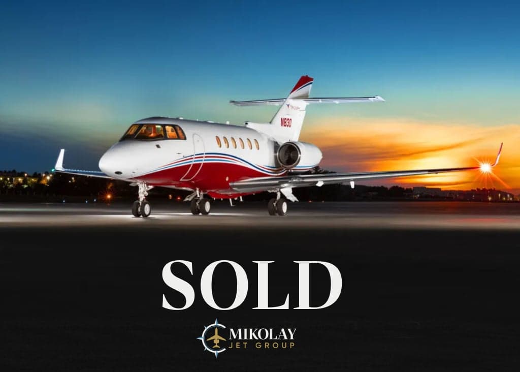 A Falcon aircraft with red and white paint scheme is parked on the tarmac at dusk, with SOLD overlaid.