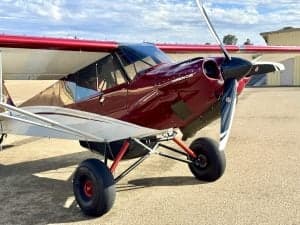 Close up of the front of a red and white Carbon Cub aircraft on the ground.