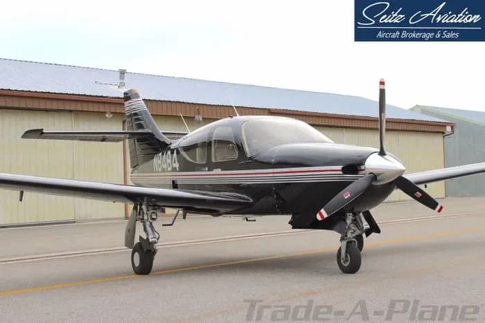 A black Beechcraft Bonanza parked on the tarmac in front of a hangar.