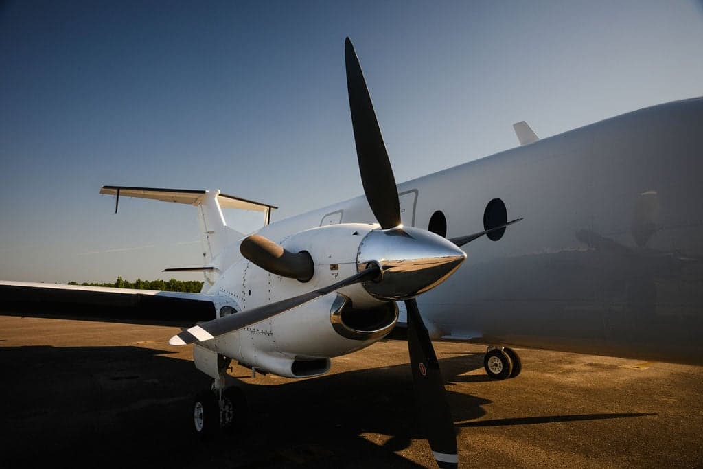 The propeller and nose of a white turboprop aircraft.
