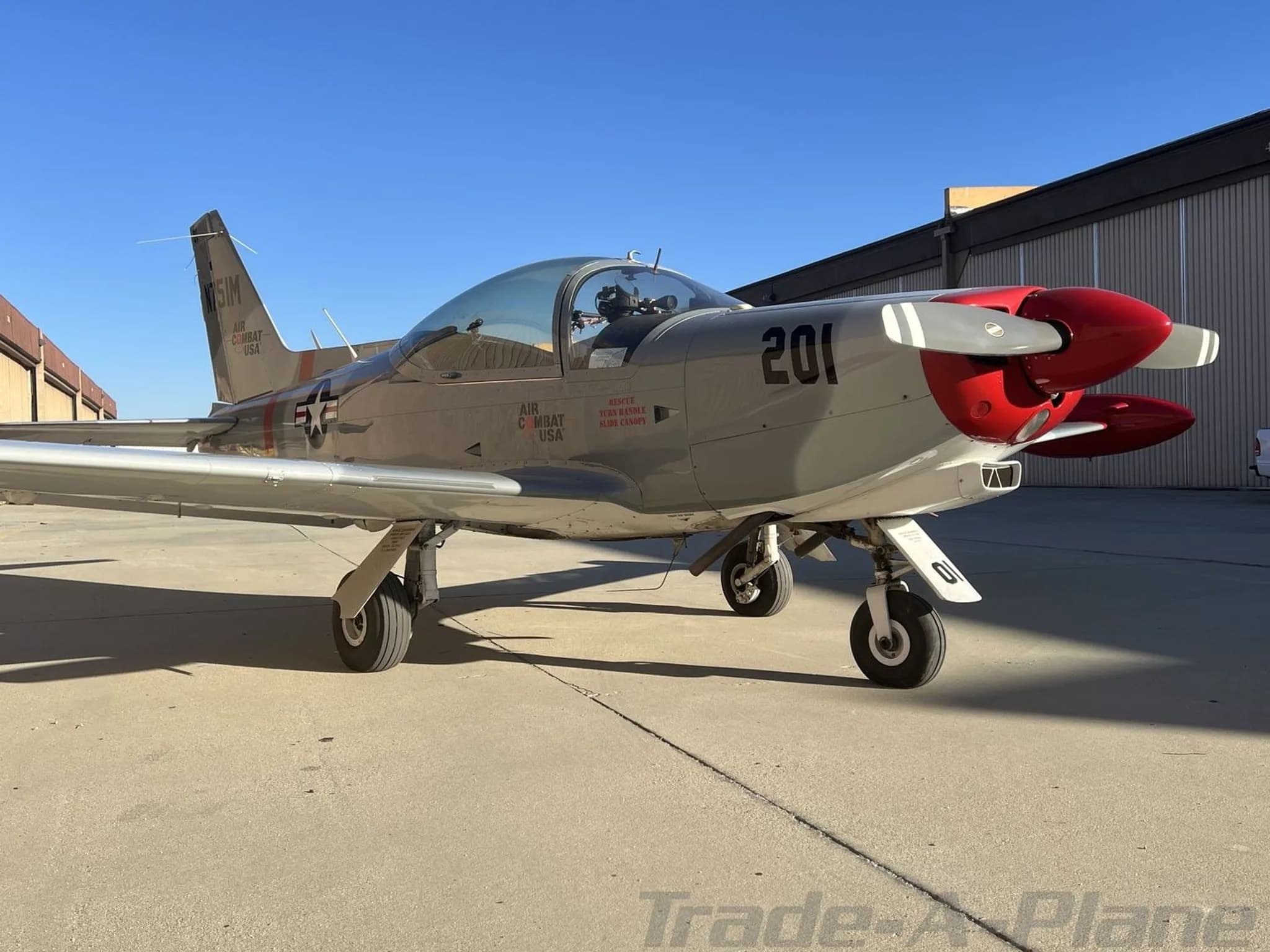 A low-angle front-right view of the grey and red Air Combat USA aircraft '201' with US Air Force star insignia.