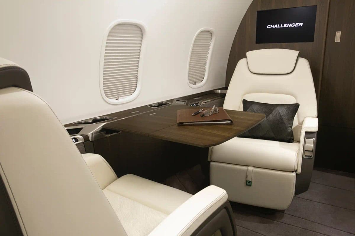 Interior of the aircraft featuring a table, seats, and a monitor.