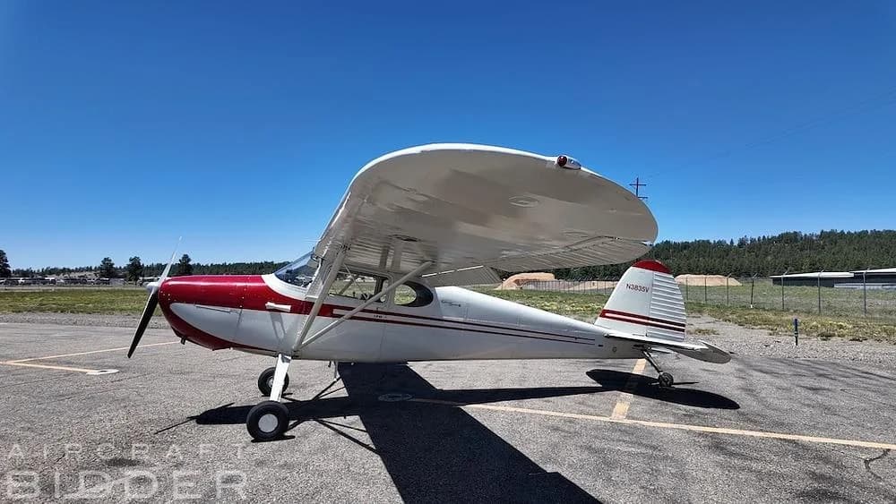 A side view of a red and white 1950 Cessna 170A aircraft (N3835V) parked on an asphalt surface.