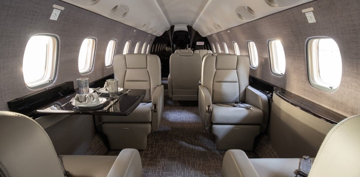 View of the aircraft cabin with gray leather seats and a table set for dining.