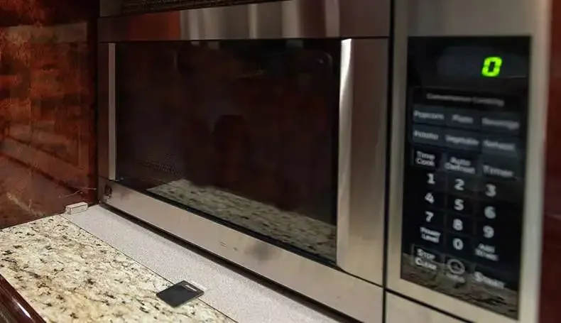 A stainless steel microwave oven with a digital display and keypad, installed in the aircraft's galley.
