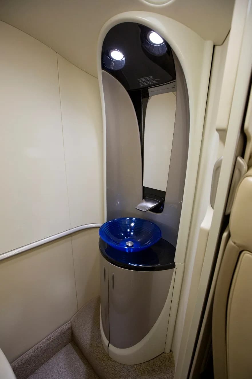 A compact lavatory or galley area featuring a blue glass sink and a mirror.