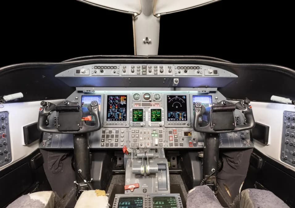 The cockpit of a business jet, featuring multiple digital displays and control yokes.