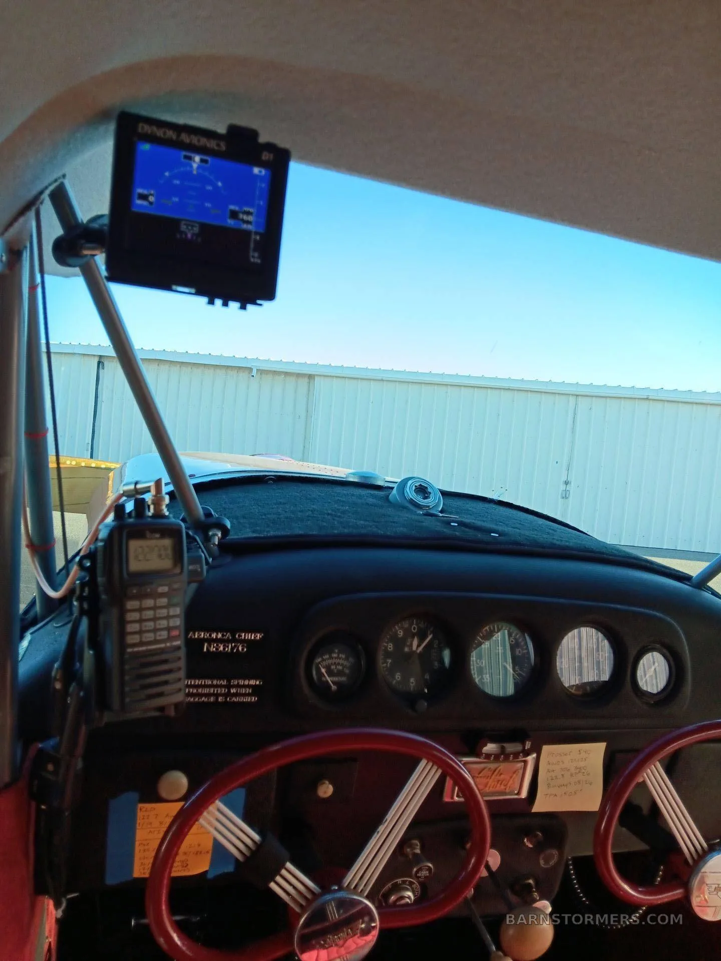 The cockpit of an Aeronca Chief, showing the instrument panel with red yokes, a radio, and a Dynon Avionics display mounted above.