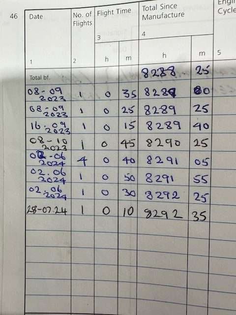 Close-up of a logbook page with handwritten flight time entries.