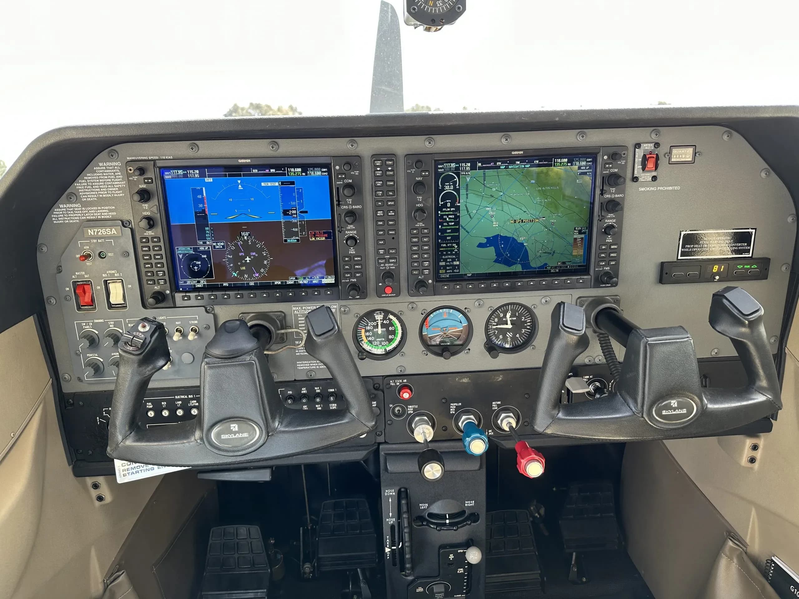 The cockpit of aircraft N726SA, featuring a modern glass panel with two large displays, traditional gauges, and dual control yokes.