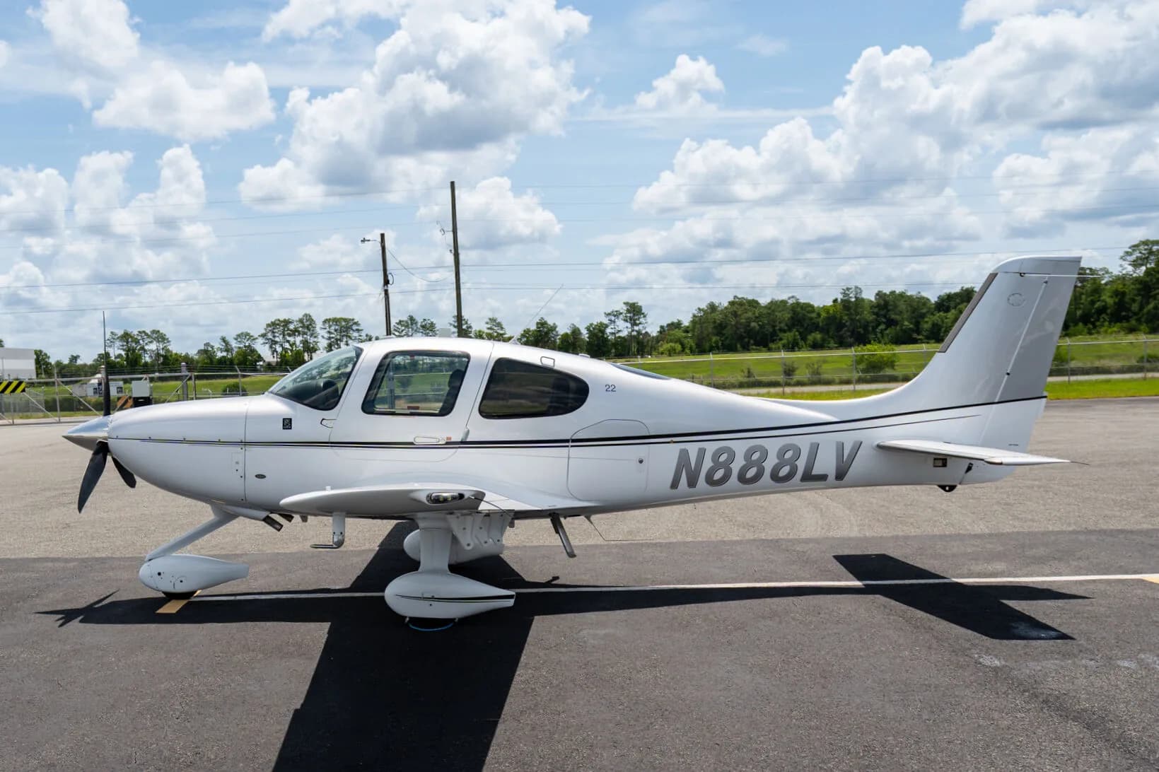 Side view of a silver Cirrus SR22 aircraft (N888LV) parked on an airfield.