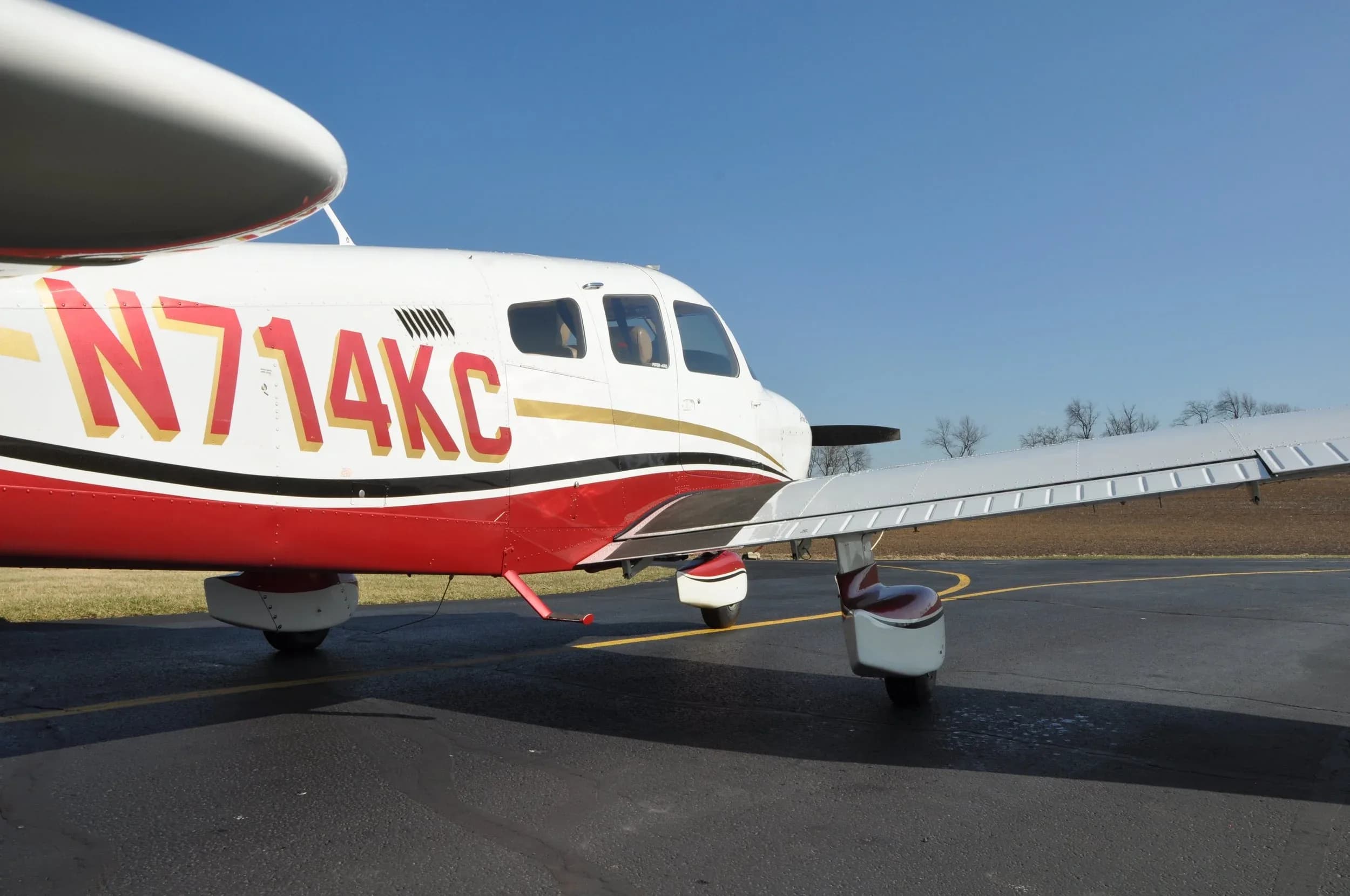 Close-up of a Piper Archer III aircraft with a white and red paint scheme on the tarmac.