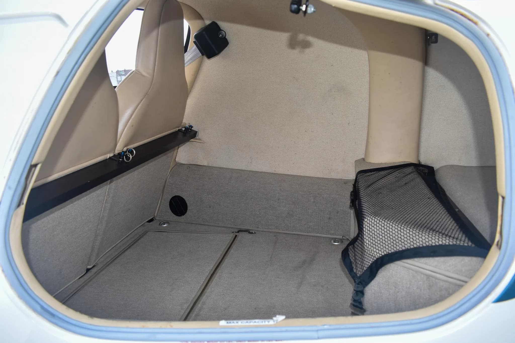 The rear baggage compartment of the Columbia 400 aircraft, showing a cargo net and tan upholstery.