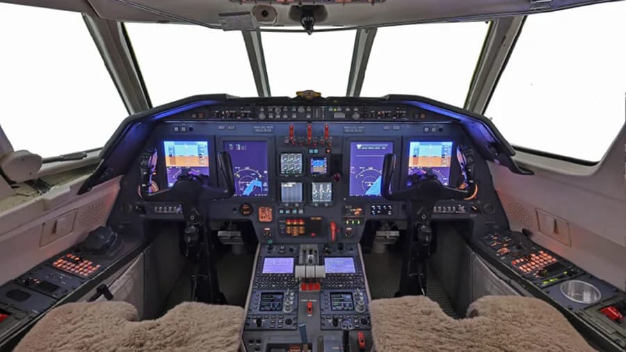 The modern glass cockpit of a business jet with multiple digital display screens.