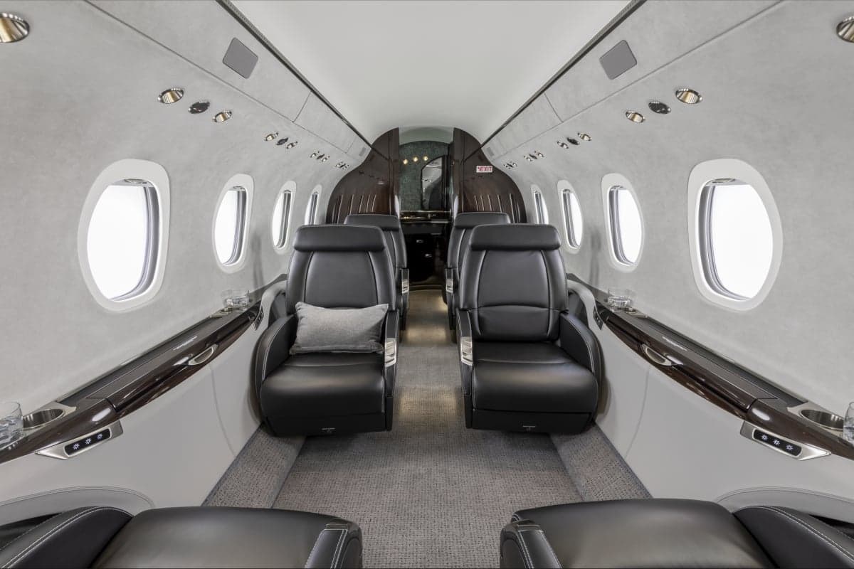 A view of the Citation Latitude cabin featuring black leather seats and a neutral color scheme.