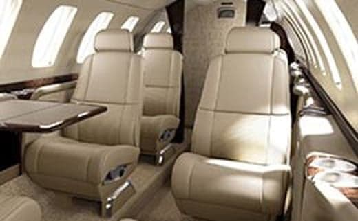 A view of the interior of a private jet with leather seats and a table.