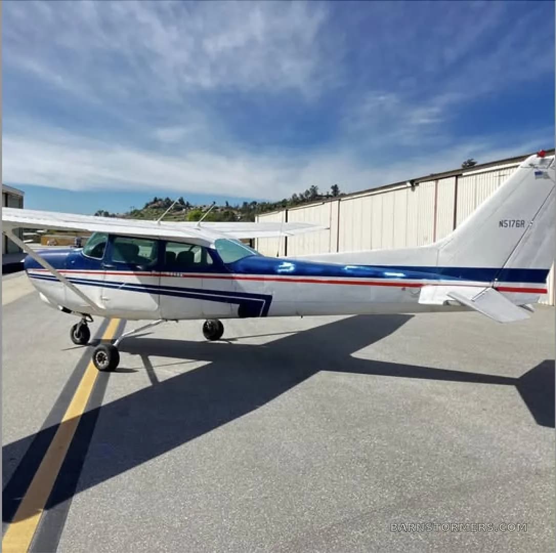 A side view of a white and blue single-engine propeller aircraft with tail number N5176R on an airport tarmac.