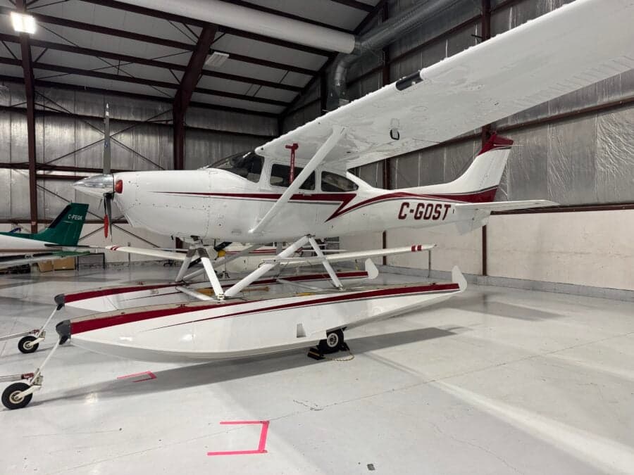 A Cessna 206 on floats is parked in a hangar.